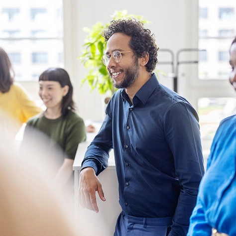 Ein motivierter Geschäftsmann im Büro, umgeben von Kollegen, symbolisiert berufliches Networking und Erfolg, ideal für Unternehmens- und Karrierebilder.