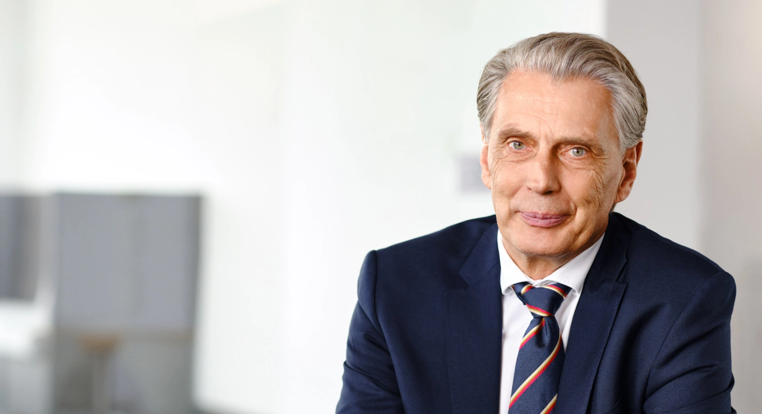 Erfahrener Geschäftsmann im Beratungsgespräch, stilvoll gekleidet, in moderner Büroumgebung, Fokus auf Business Consulting, professionelle Präsenz, innovative Lösungen.