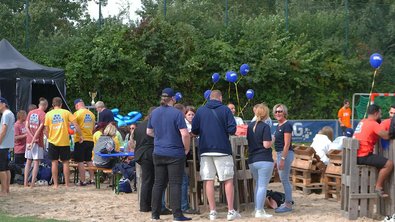 ZAG Fanveranstaltung bei einem Outdoor-Event mit Menschen, Ballons und ZAG-Logo, sportliche Atmosphäre, Gemeinschaft und Engagement, Fußballspiel, sommerliches Wetter, Promotion und Markenpräsenz.
