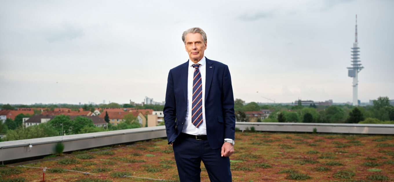 Modernes Imagefoto eines Mannes im Anzug auf einem Dach mit Stadtblick, ideal für Unternehmenswebsites, Business-Profis, Management, Führungskräfte, und Finanzbranche.